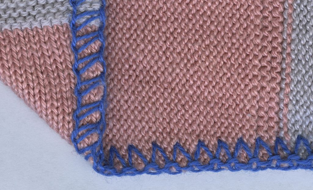 A piece of pink knitted fabric with a blue 3-thread overlock stitch on its edge